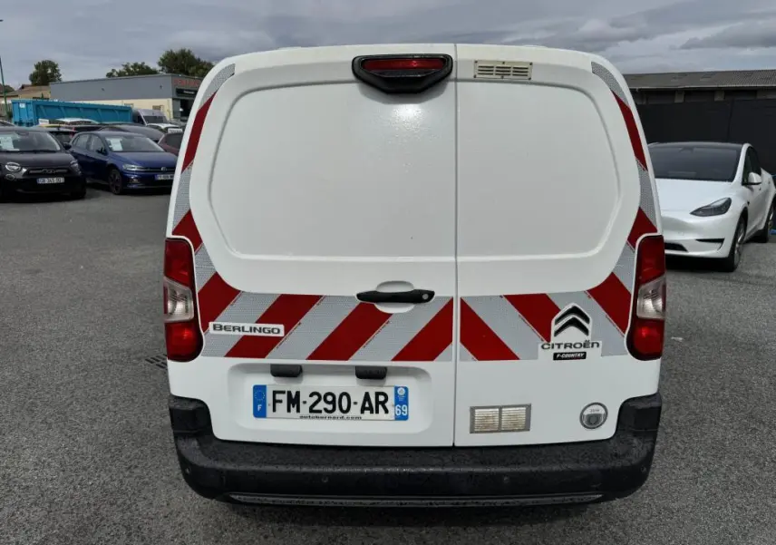 Vue arrière d'un Citroën Berlingo blanc avec bandes réfléchissantes rouges et blanches et plaques d'immatriculation françaises.