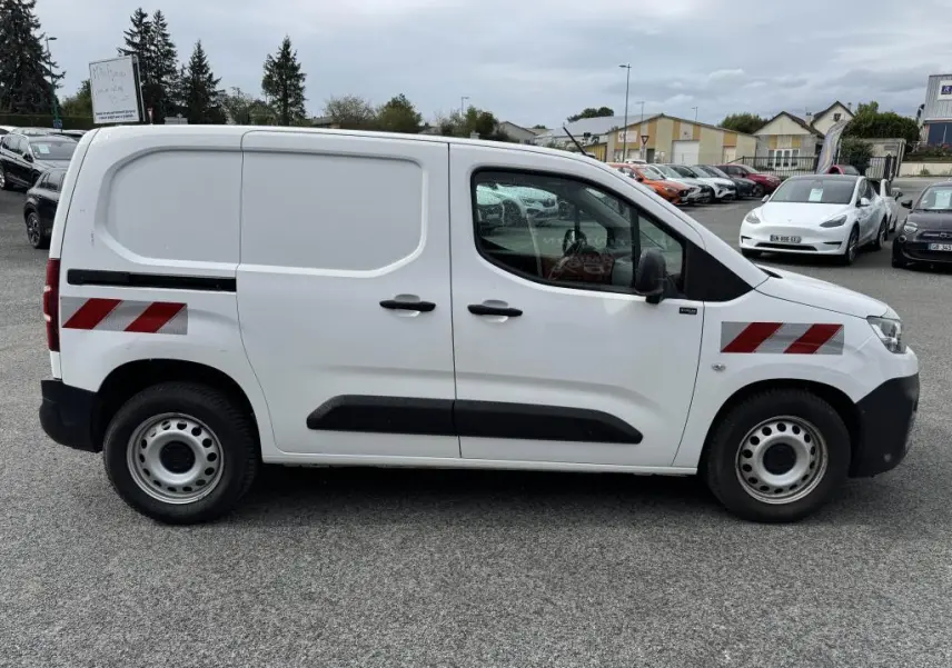 Vue latérale droite d'un utilitaire Citroën Berlingo blanc avec bandes réfléchissantes rouges et noires sur les portes.