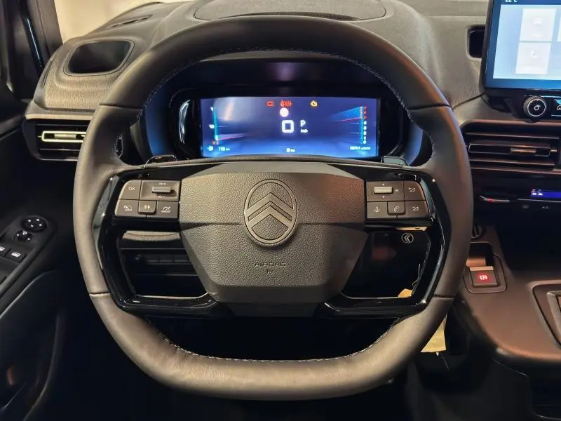 Vue frontale du volant cuir noir du Citroën Berlingo Fourgon 2025 avec tableau de bord numérique et commandes intégrées.
