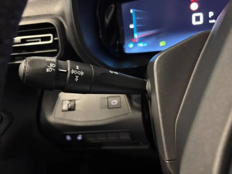 Gros plan sur la manette des phares et clignotants du CITROEN BERLINGO Fourgon noir Perla Nera nacré, tableau de bord en arrière-plan.