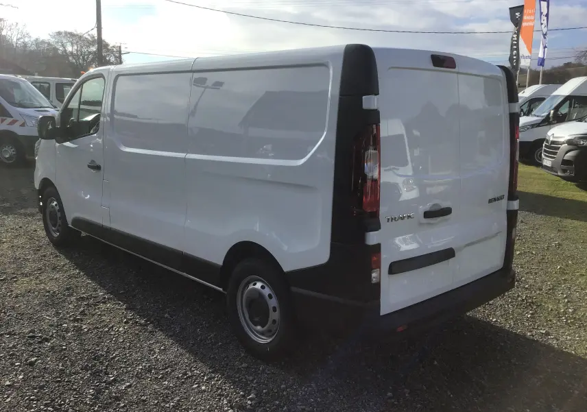 Vue 3/4 arrière droite d’un Renault Trafic Fourgon blanc 2025 avec panneaux latéraux pleins et feux arrière verticaux.
