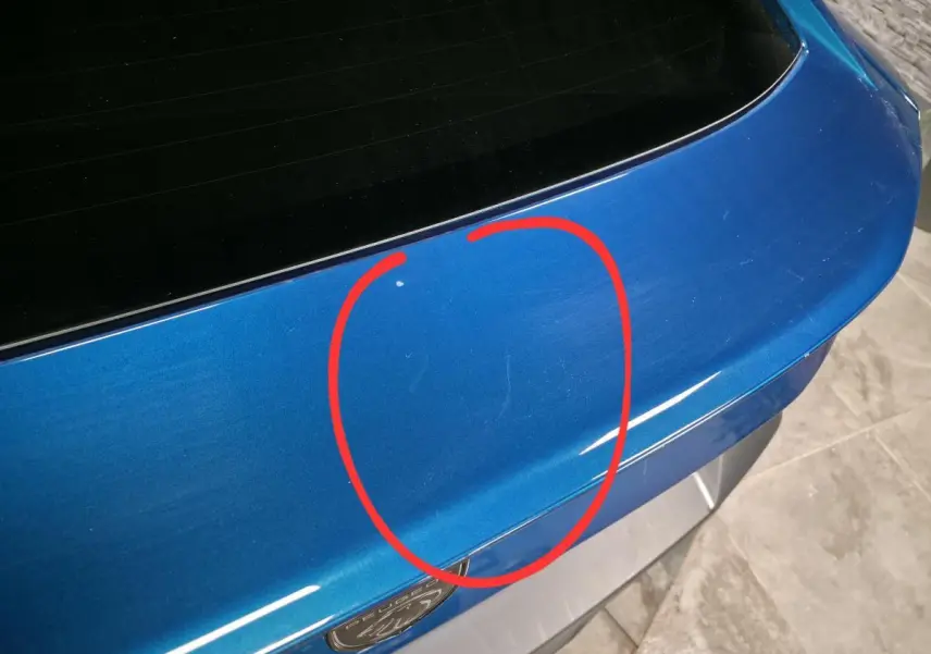 Détail du coffre arrière bleu métallisé d'une Peugeot 408 2024 avec rayures visibles au centre.