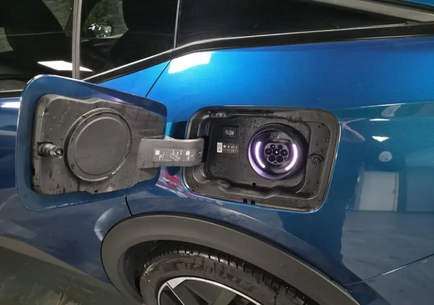 Prise de recharge ouverte côté gauche arrière d'une Peugeot 408 hybride rechargeable bleu métallisé.