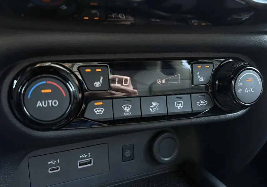 Gros plan sur la console de climatisation noire du Nissan Juke 2024 avec commandes chauffantes et ventilation automatique.