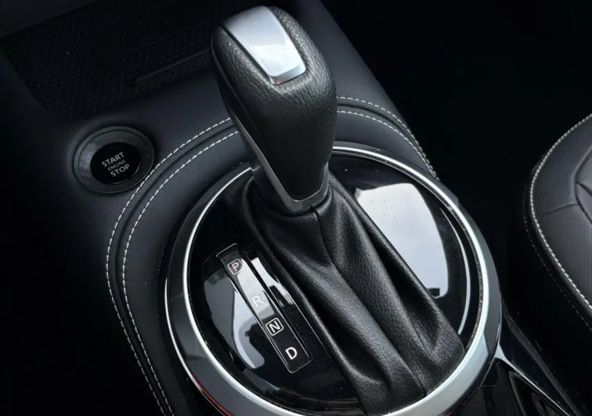 Gros plan sur le levier de vitesses automatique noir avec surpiqûres blanches dans l’habitacle du Nissan Juke 2024.