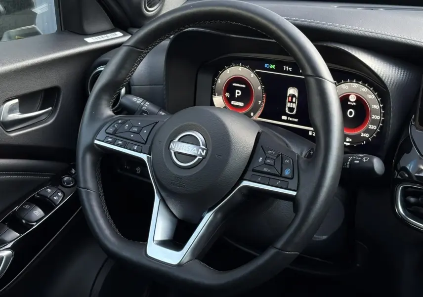 Vue rapprochée du volant noir et du combiné d'instruments digital du Nissan Juke 2024 côté conducteur.