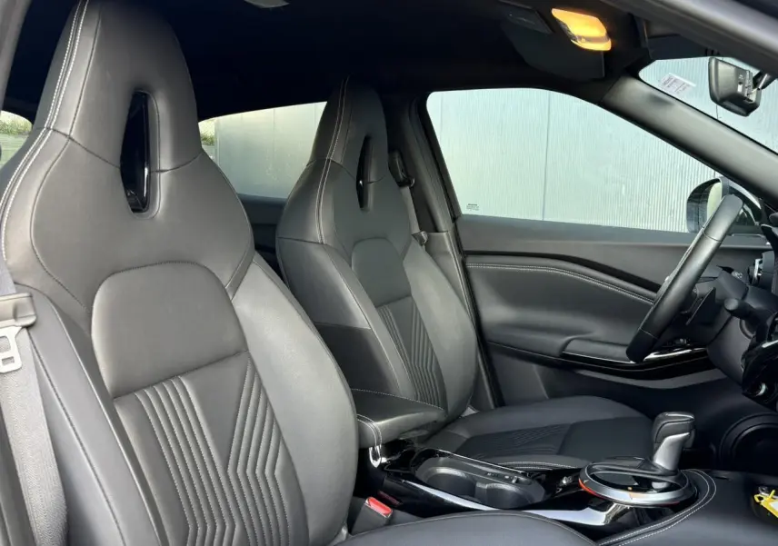 Vue intérieure côté avant droit du Nissan Juke 2024 avec sièges sport noirs et console centrale brillante.