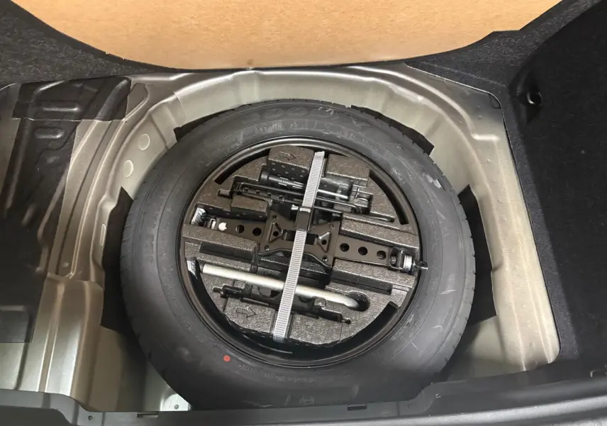 Roue de secours avec outils de bord dans le coffre d’un Skoda Kamiq 2023, vue plongeante sur le compartiment.