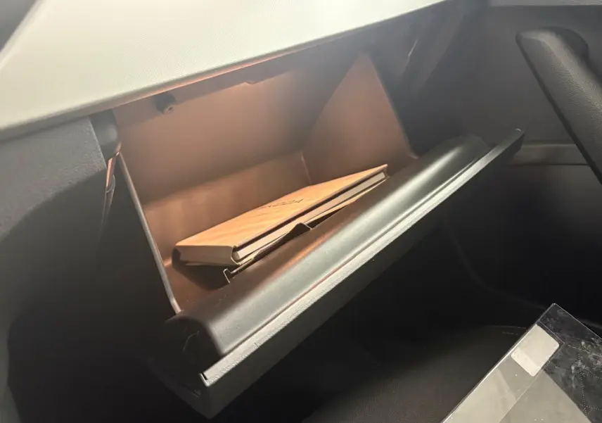 Boîte à gants ouverte côté passager dans un Skoda Kamiq 2023 gris graphite avec manuel à l’intérieur.