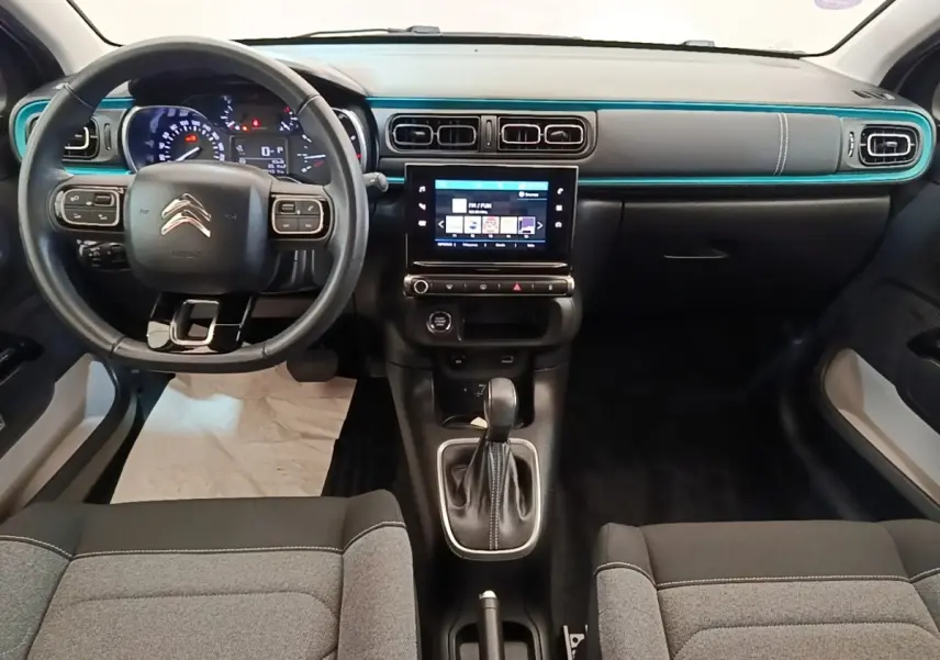 Vue intérieure avant de la Citroën C3 2022, tableau de bord noir avec bande décorative turquoise et écran tactile central.