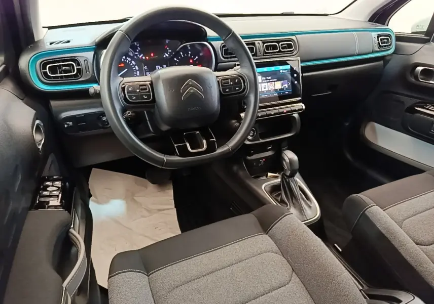 Vue intérieure avant droite du tableau de bord noir et bleu turquoise de la Citroën C3 2022 avec volant cuir et écran tactile.