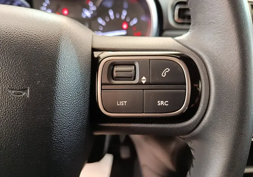 Gros plan sur les commandes du volant cuir noir de la Citroën C3 2022, boutons de gestion audio et appel.