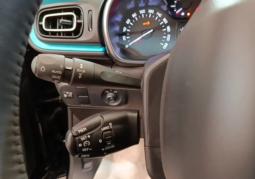 Vue rapprochée du tableau de bord côté gauche d’une Citroën C3 noire, avec commandes de régulateur et compteur lumineux.