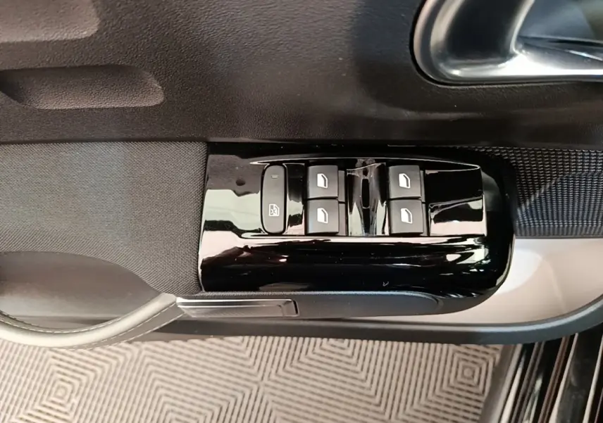 Gros plan sur les commandes de lève-vitres côté conducteur de la Citroën C3 noire, finition Shine Pack 2022.