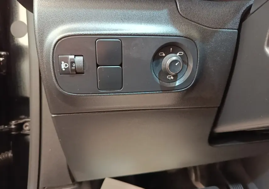 Gros plan sur les commandes de réglage des phares et des rétroviseurs côté gauche intérieur d'une Citroën C3 noire 2022.
