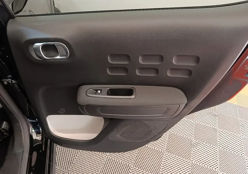 Vue intérieure de la porte arrière gauche noire d'une Citroën C3 2022 avec panneau de commande et haut-parleur intégré.