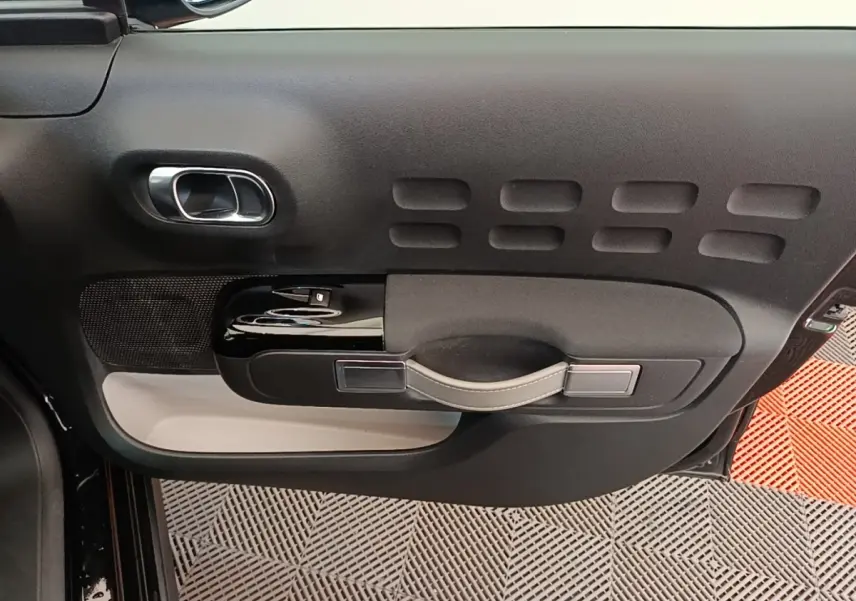 Vue rapprochée de la porte côté gauche de la Citroën C3 noire, avec poignée et commandes de vitre en noir brillant.