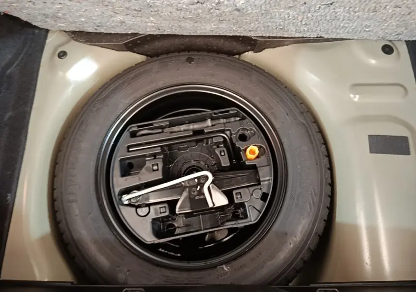Gros plan sur la roue de secours et son rangement sous le plancher du coffre d'une Citroën C3 noire 2022.