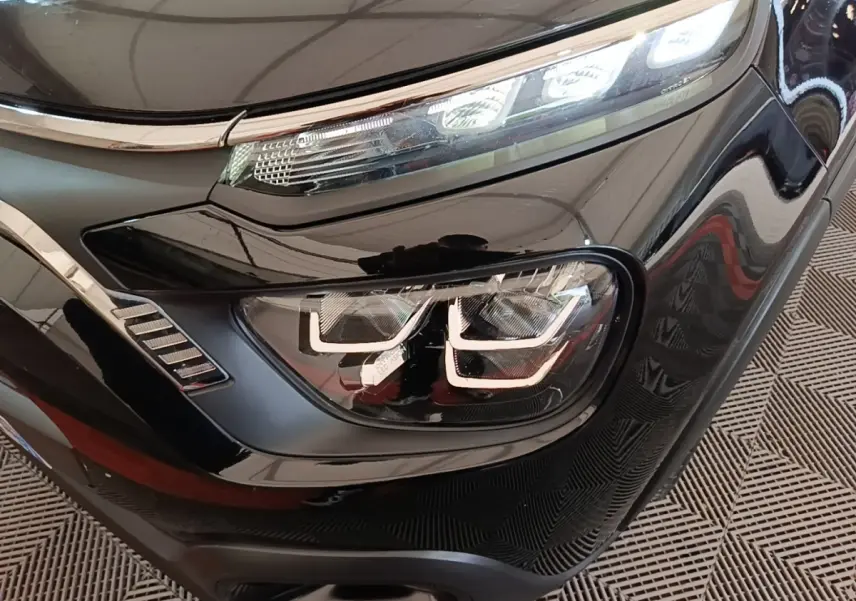 Gros plan sur le phare avant droit noir brillant de la Citroën C3 PureTech 110 Shine Pack 2022 avec éclairage LED distinctif.