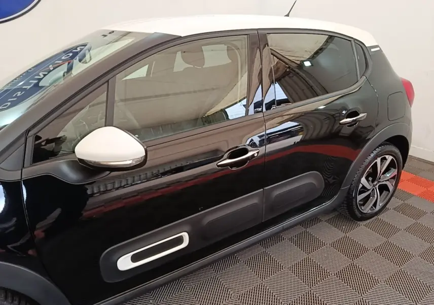 Vue latérale droite d'une Citroën C3 noire avec toit blanc et rétroviseur blanc, soulignant les protections latérales.