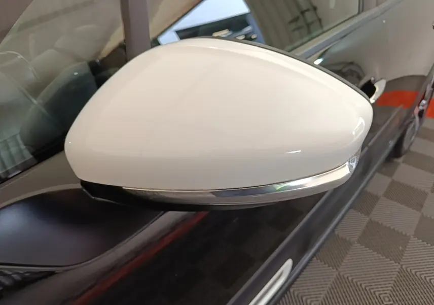 Gros plan sur le rétroviseur blanc côté gauche d'une Citroën C3 noire, avec clignotant intégré chromé.