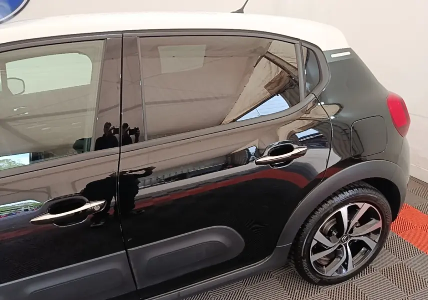 Vue latérale droite d'une Citroën C3 noire avec toit blanc et jantes alliage distinctives.