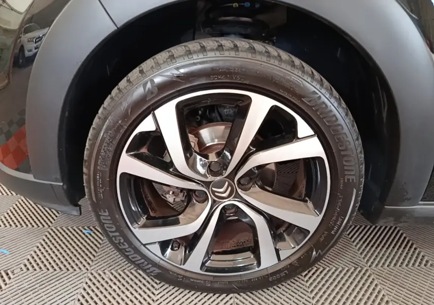 Gros plan sur la roue avant gauche noire d'une Citroën C3 2022 avec jante alliage bicolore et logo Citroën central.
