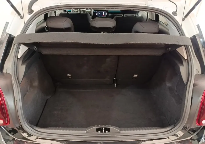 Vue arrière ouverte sur le coffre noir d'une Citroën C3 PureTech 110 Shine Pack 2022, intérieur et tablette de coffre visibles.