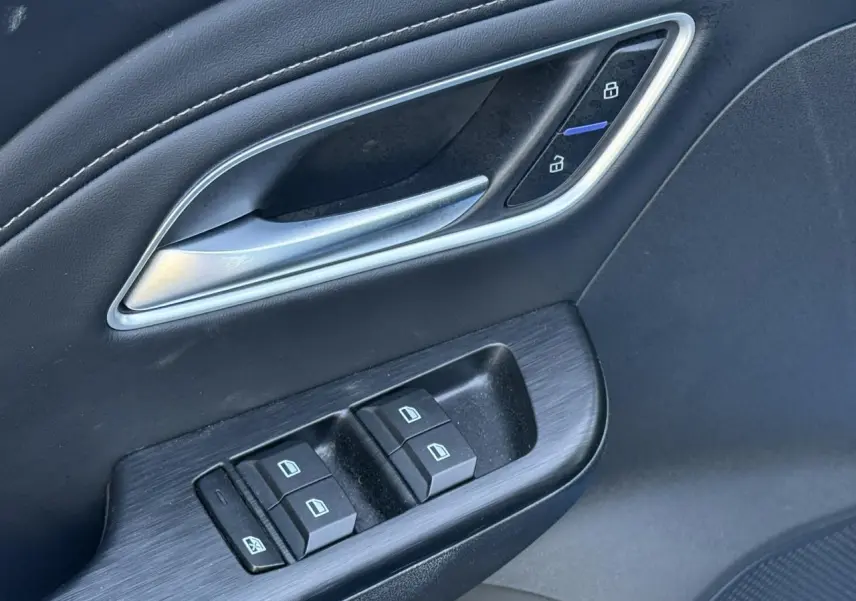 Gros plan sur la porte côté conducteur du MG ZS 1.5 Hybrid+ 197 Luxury avec commandes de vitres et verrouillage en similicuir noir.