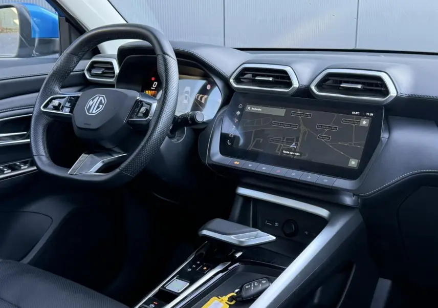 Vue intérieure côté conducteur du MG ZS 1.5 Hybrid+ 197 Luxury 2025, tableau de bord noir avec écran tactile et volant cuir.