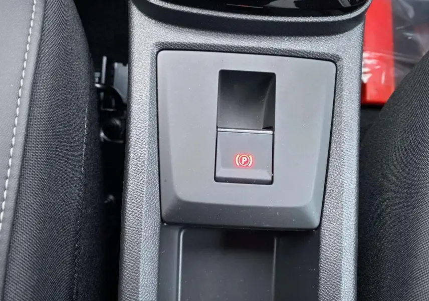 Gros plan sur le bouton de frein de stationnement électrique rouge dans la console centrale du Citroën C3 Aircross 2025.