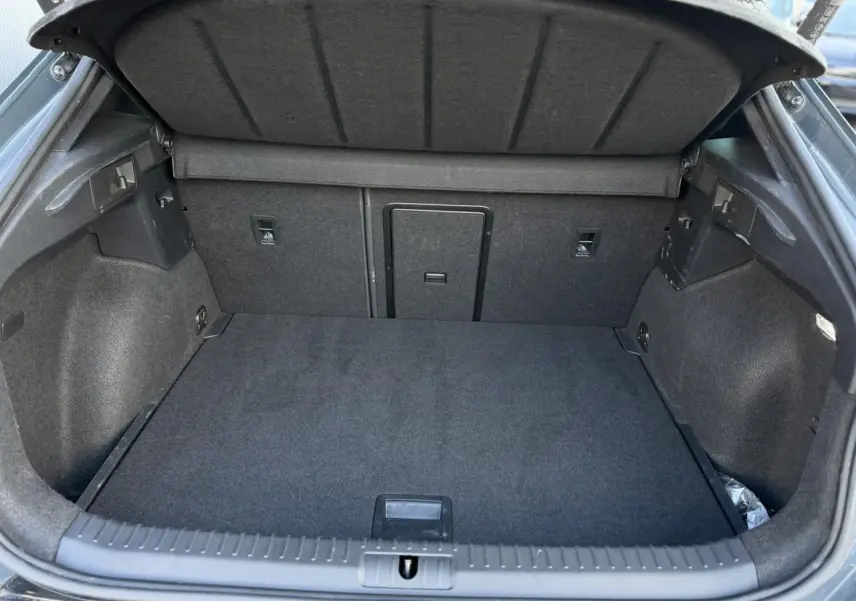 Coffre ouvert vu de l'arrière d'un CUPRA Formentor Bleu Fjord, espace de chargement vide et doublure noire.