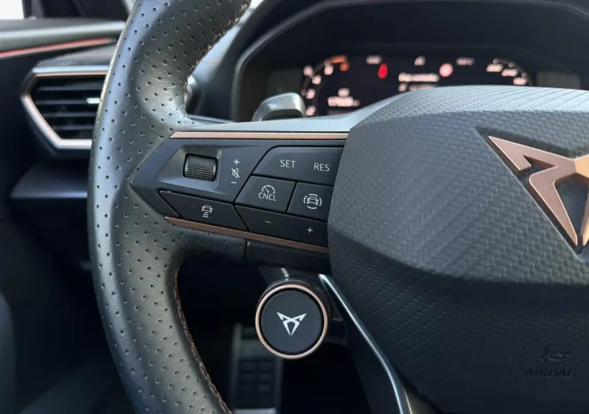 Gros plan sur le volant cuir perforé noir du CUPRA Formentor 2025 avec commandes multifonctions et logo cuivre central.