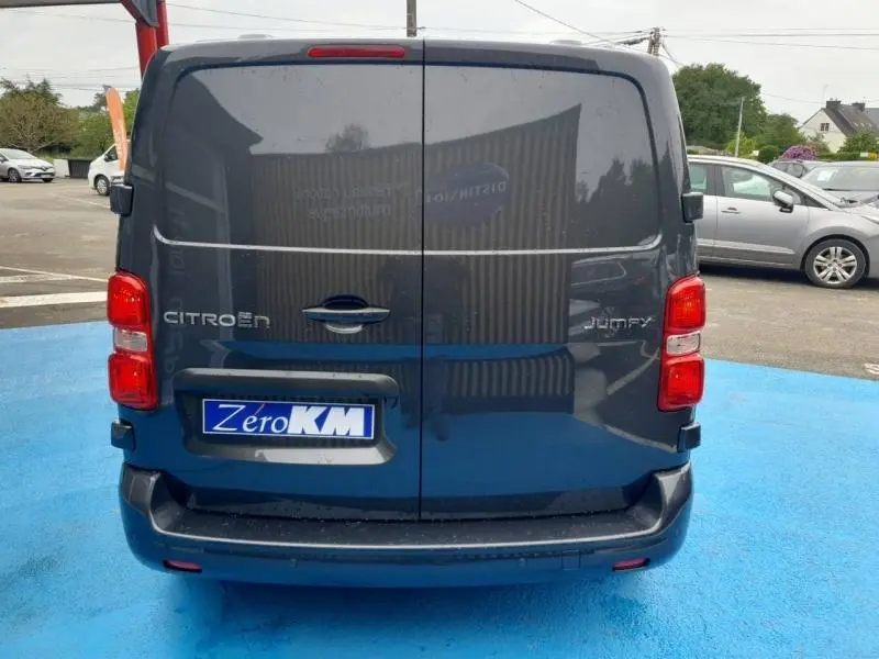 Vue arrière d'un Citroën Jumpy gris titane métal avec portes battantes et feux arrière rouges visibles.