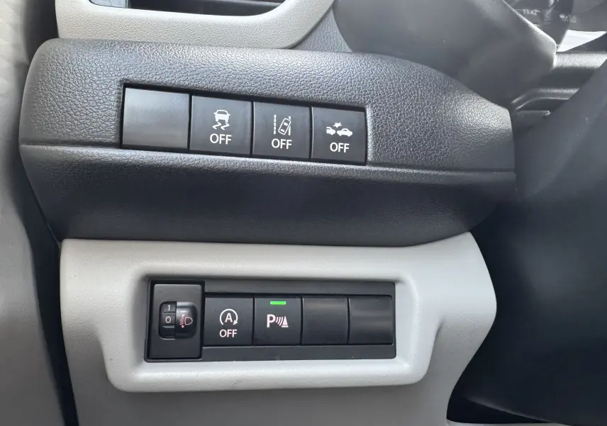 Panneau de commandes avec boutons d'assistance à la conduite dans l'habitacle d'une Suzuki Swift 1.2 Hybrid Privilege Auto bleu.