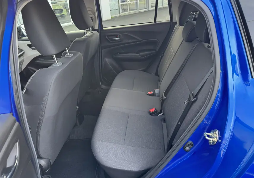Vue intérieure côté droit sur la banquette arrière noire d'une Suzuki Swift 1.2 Hybrid Privilege bleu 2025 avec porte ouverte.