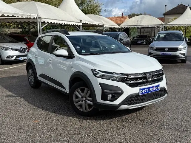 Vue 3/4 avant d'une Dacia Sandero Stepway blanche 2021 avec détails noirs et toit ouvrant en concession.