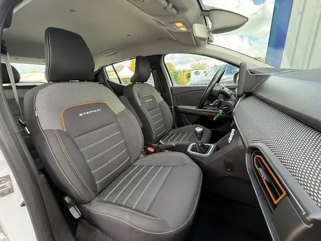 Vue intérieure côté conducteur de la Dacia Sandero Stepway 2021 avec sièges noirs marqués Stepway et détails orange.