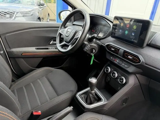 Intérieur côté conducteur de la Dacia Sandero Stepway blanche 2021, avec tableau de bord moderne et boîte manuelle visible.