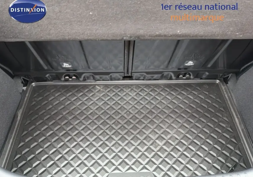 Vue plongeante sur le coffre ouvert d'une Toyota Aygo X noire, mettant en valeur le tapis de coffre texturé.