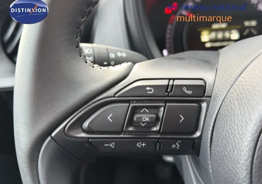 Gros plan sur les commandes au volant côté gauche d'une Toyota Aygo X noire, avec boutons multifonctions visibles.