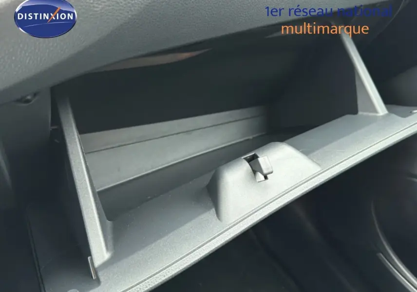 Gros plan sur la boîte à gants ouverte de la Toyota Aygo X noire, intérieur en plastique gris sombre.