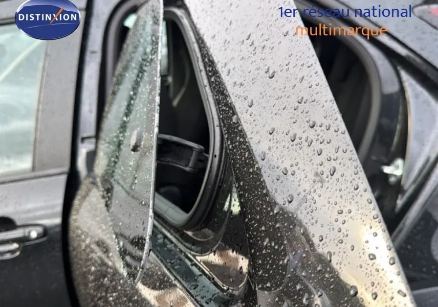 Gros plan sur le rétroviseur côté gauche d'une Toyota Aygo X noire 2025, avec gouttes de pluie visibles sur la carrosserie.