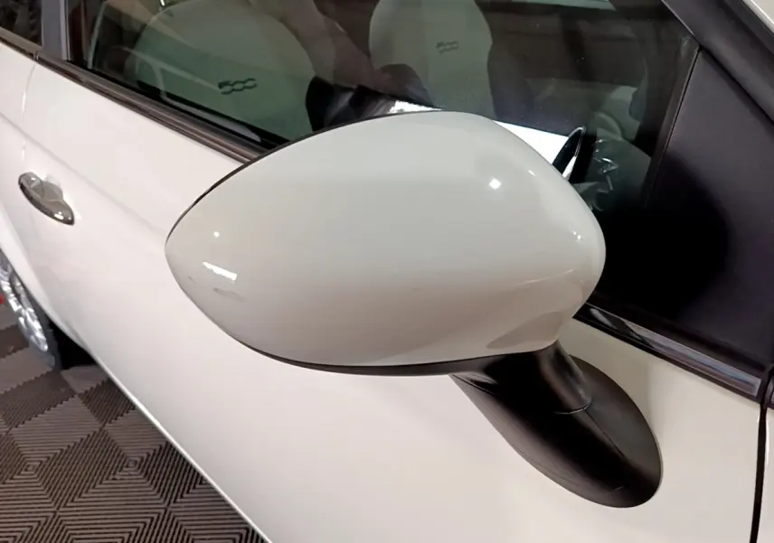 Rétroviseur blanc côté gauche d'une Fiat 500 Hybrid 2021, avec porte et siège intérieur visibles.