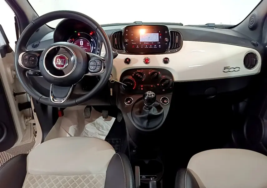 Vue intérieure avant de la Fiat 500 Hybrid blanche, tableau de bord avec écran tactile et volant multifonctions cuir.