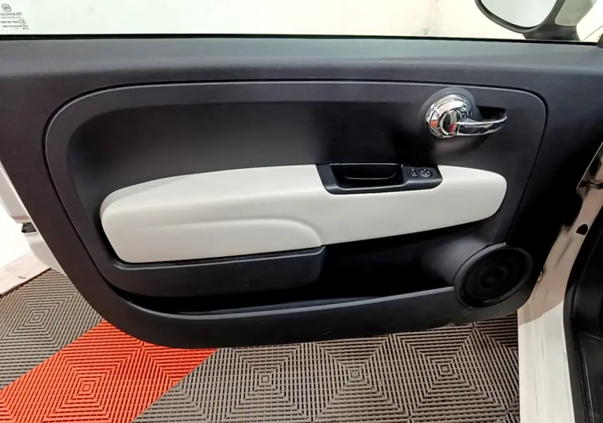 Vue rapprochée de la porte avant droite blanche de la FIAT 500 Dolcevita avec garniture intérieure bicolore noire et beige.