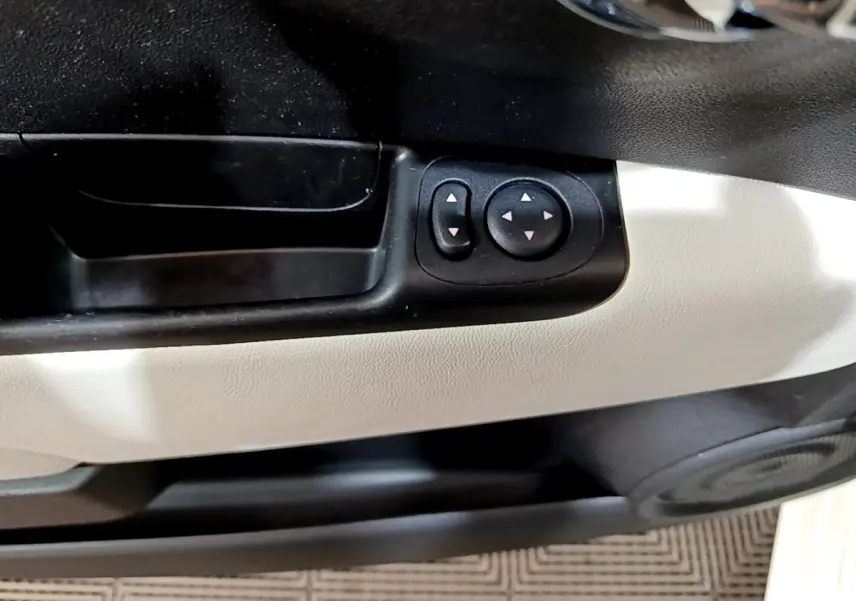 Gros plan sur les commandes de réglage des rétroviseurs noirs sur la porte intérieure blanche d'une Fiat 500 Hybrid 2021.