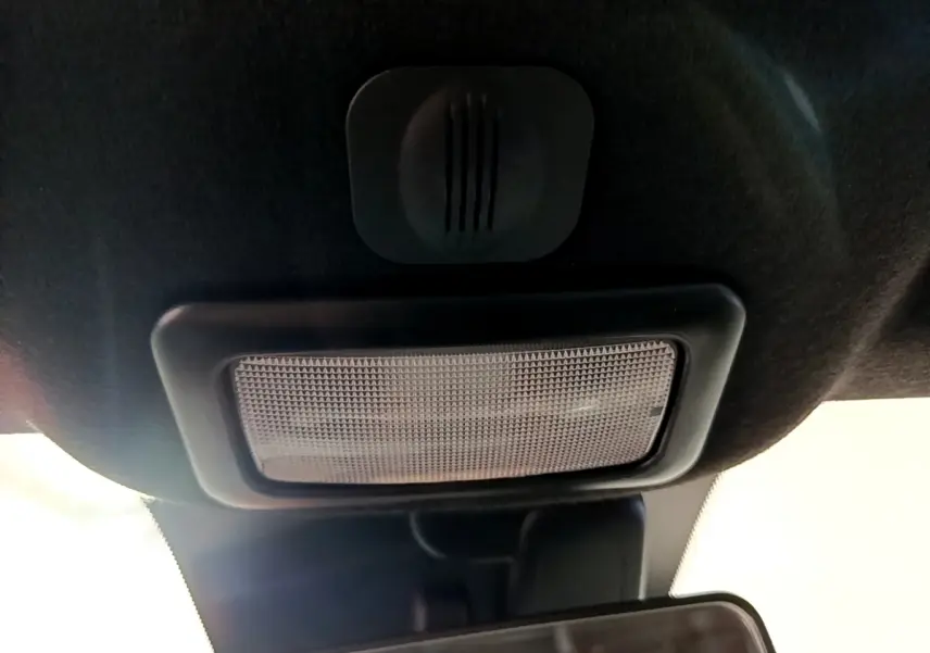 Plafonnier intérieur noir vu de dessous dans une Fiat 500 blanche, avec miroir de courtoisie partiellement visible.