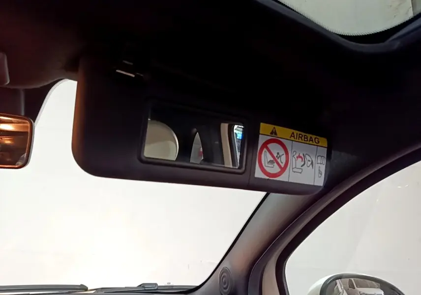 Intérieur de la Fiat 500 Hybrid 2021, vue du pare-soleil côté conducteur avec miroir et avertissement airbag visible.
