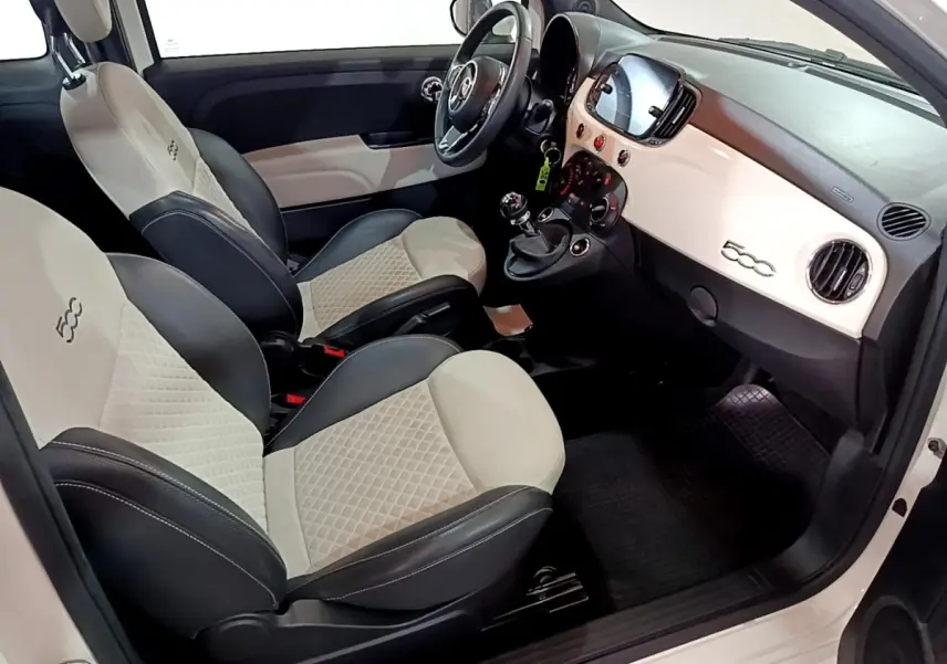 Vue intérieure côté conducteur de la Fiat 500 Hybrid blanche, avec sièges bicolores et tableau de bord épuré.